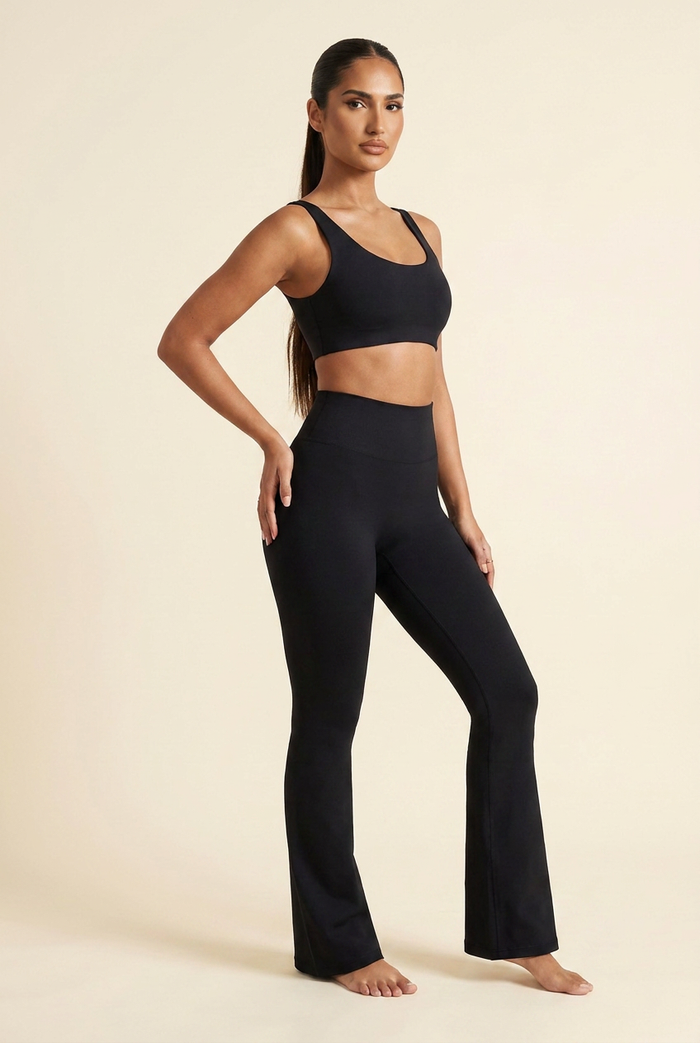Kovelle high waist flare leggings in black, three quarter stance with hand on hip showing the bell hem, on model