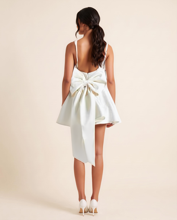 Kovelle White Satin Bow-Back Mini Dress in white, oversized back bow with trailing sash, back view, on model