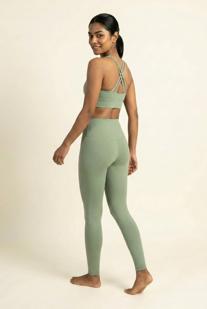 Kovelle cross back leggings set in sage, crossed back straps and high waist leggings, walking away glancing back, on model