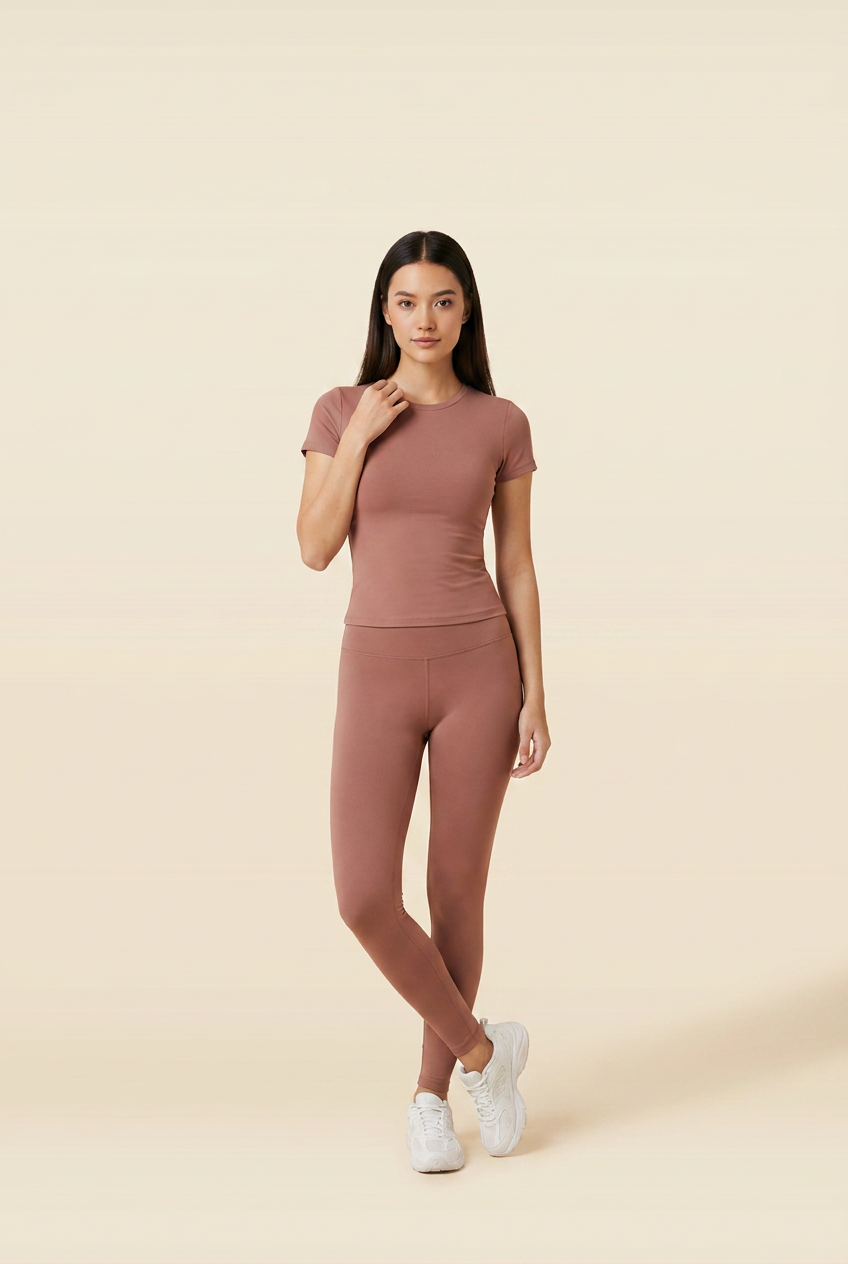 Kovelle round neck legging set in rose brown, feet crossed with a hand at her collarbone, on model
