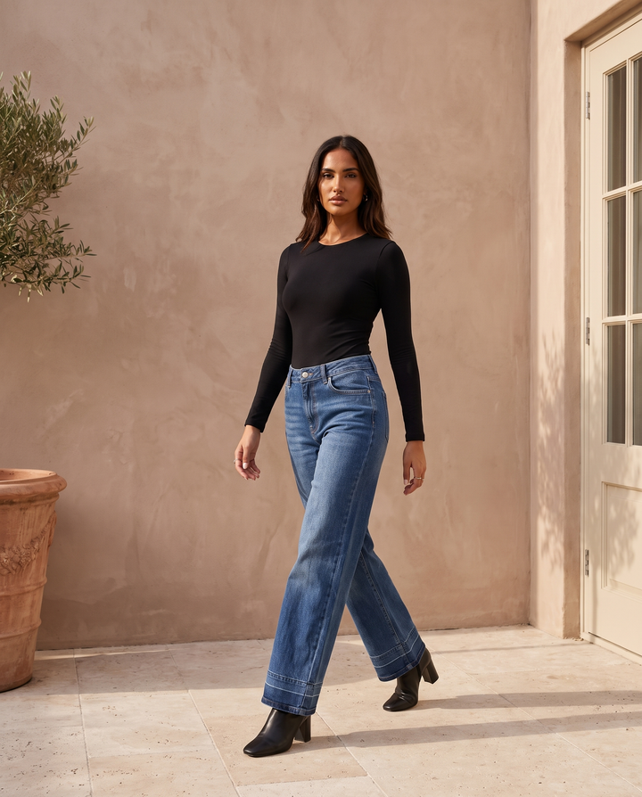 Kovelle mid rise wide leg jeans with black top, on model walking through the Kovelle House courtyard