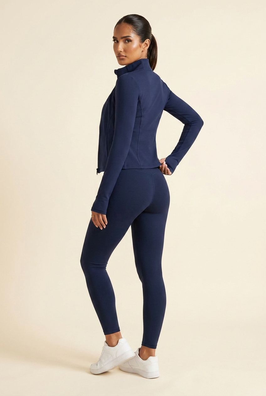 Kovelle zip through gym jacket in navy, three quarter back view tugging the hem, on model