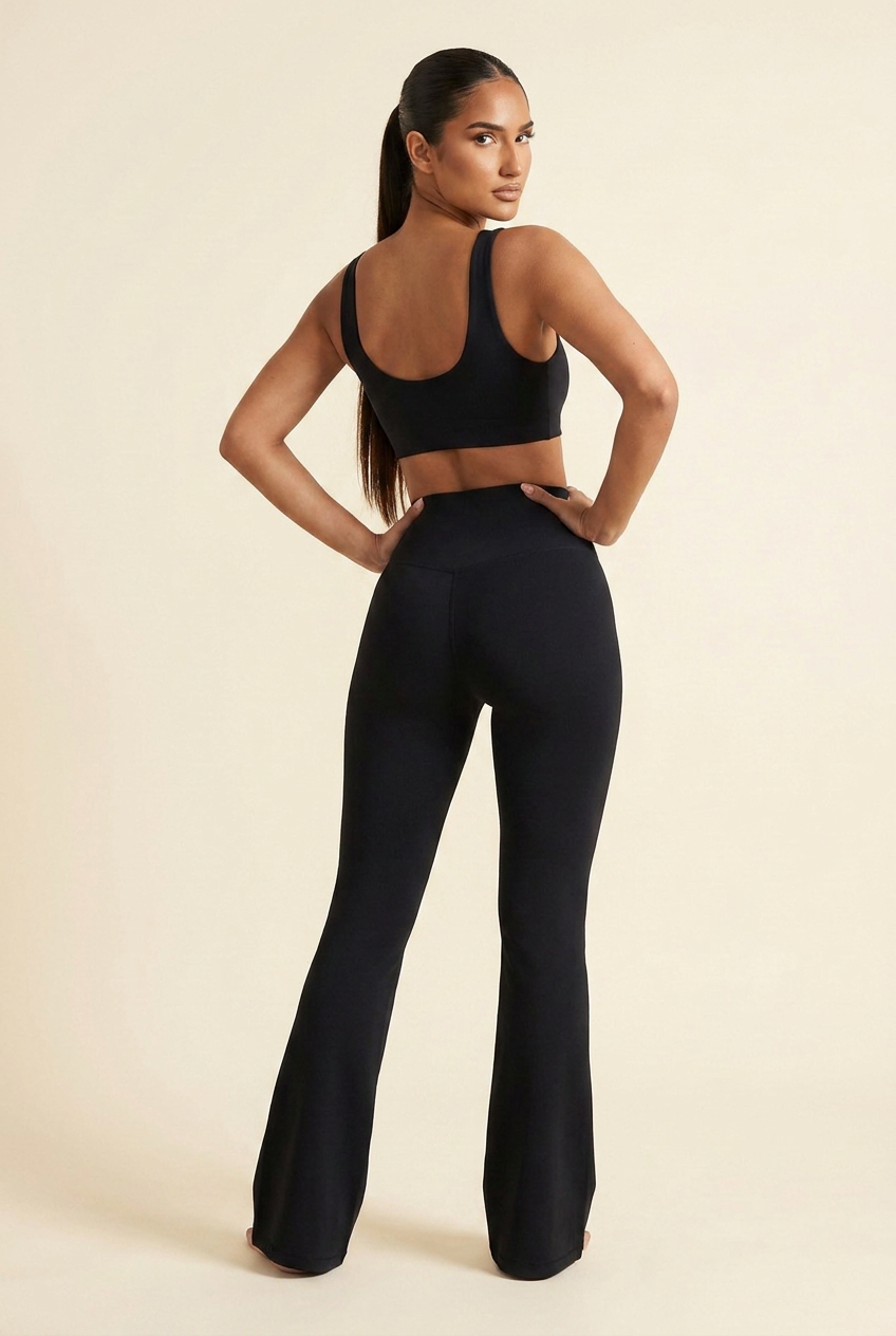 Kovelle high waist flare leggings in black, back view with hands on hips looking over her shoulder, on model