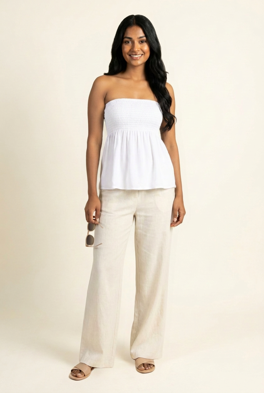 Kovelle shirred bandeau babydoll top in white, front view on model with linen trousers